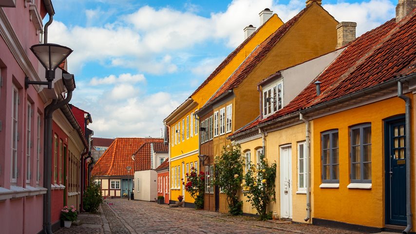 Farvede boliger langs gågade med brosten